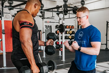 Athlete performing bicep curls with blood flow restriction cuffs on